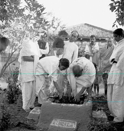 Foto de Mahatma Gandhi y Abha Gandhi plantando un árbol tulsi en el Ashram Sevagram, agosto de 1944, detrás de Abha Gandhi Pyarelal Nayar, llevando a su sobrina Nandini, sobrino nieto de Prabhudas Gandhi de Mahatma Gandhi - Imagen libre de derechos