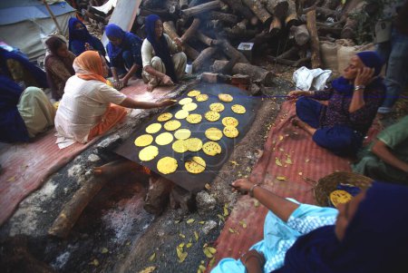 Photo for Sikh devotees making makai di rotis corn flour bread in community kitchen, 300th year of consecration of perpetual Guru Granth Sahib, Sachkhand Saheb Gurudwara in Nanded, Maharashtra, India - Royalty Free Image
