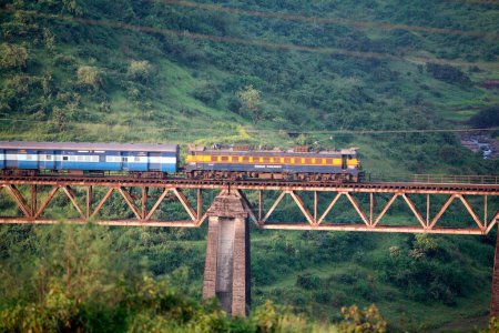 Téléchargez les photos : Train Indian Railways passant par un pont surélevé à Igatpuri près de Nasik dans le Maharashtra ; Inde - en image libre de droit