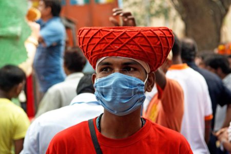 Photo for Devotee in maratha cap and protective mask for swine flu during lord ganesh ganpati festival, Bombay Mumbai, Maharashtra, India 16-August-2009 - Royalty Free Image