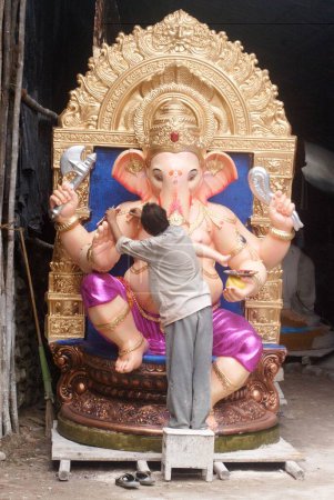 Photo for Man painting the big idol of lord Ganesh in Chitrashala ; Elephant headed god of Hindu ; Ganapati Festival at Lalbaug ; Bombay Mumbai ; Maharashtra ; India - Royalty Free Image
