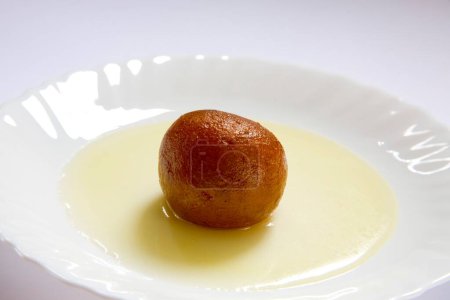 Photo for Indian sweet food Bachelor one single piece of round shape Gulabjamun Bonbon Confectionery with sugar syrup served in plate - Royalty Free Image