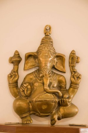 Idol of Lord Ganesh of Brass metal on wall Pune Maharashtra India Asia Dec 2011