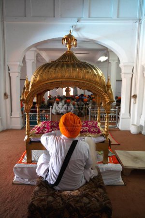 Photo for Sikh cleric waves whisk over holy Guru Granth Sahib in Anandpur Sahib Gurudwara in Rupnagar district, Punjab, India - Royalty Free Image