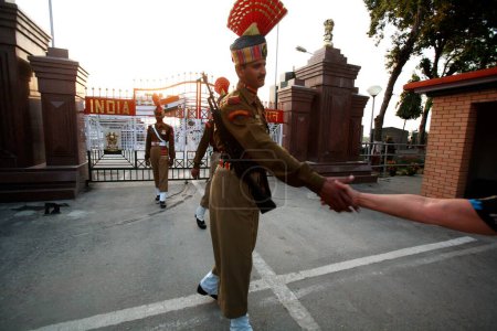 Photo for Indian border security force solider shaking hand with people during changing of guard ceremony at Wagah border, Amritsar, Punjab, India - Royalty Free Image