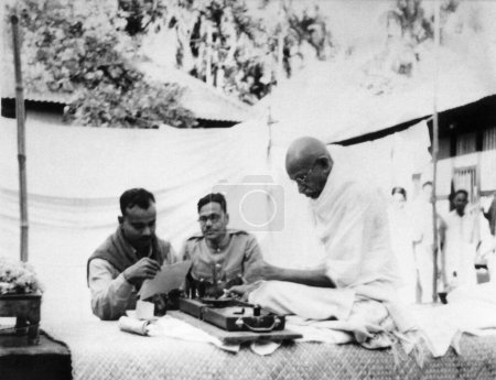Téléchargez les photos : Mahatma Gandhi filant et parlant aux inspecteurs de la police gouvernementale, Ramdevpur Noakhali, 1947, Inde - en image libre de droit