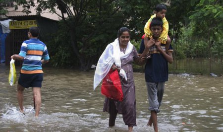Téléchargez les photos : Inondations dues aux fortes pluies, mousson, à Mumbai Bombay, Maharashtra, Inde, photos prises le 27juillet2005 à Mira Road. Pluie record de 944mm dans la ville, Exploitation forestière dans la colonie résidentielle, Personnes marchant dans l'eau, Marché - en image libre de droit