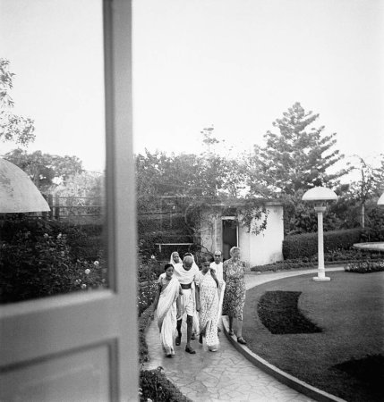 Foto de Mahatma Gandhi, con el apoyo de Abha Gandhi y otros caminando en Birla House, Mumbai, 1945, Pyarelal Nayar, Agatha Harrison, India - Imagen libre de derechos