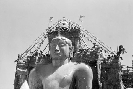 Photo for Jain Devotees pouring milk on the head of 58.8 feet monolithic Statue of jain saint Gomateshwara (Lord Bahubali) in Mahamastakabhisheka (head anointing ceremony) on the Vindhyagiri hill, Shravanbelagola, Karnataka, India - Royalty Free Image