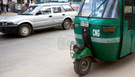 Foto de Escena callejera, verde auto rickshaw tempo y coche en el tráfico por carretera en Dhaka, Bangladesh - Imagen libre de derechos