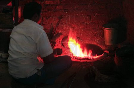 Foto de Hombre sentado quemando utensilios de cobre Pune Maharashtra India Asia Feb 2012 - Imagen libre de derechos