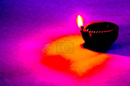 Foto de Bellas artes, una sola lámpara de aceite de arcilla diya una fuente de luz como llama sobre fondo colorido - Imagen libre de derechos