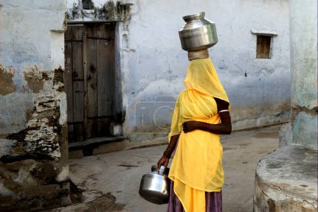 Téléchargez les photos : Femme portant de l'eau dans des pots ; Dilwara ; Rajasthan ; Inde - en image libre de droit