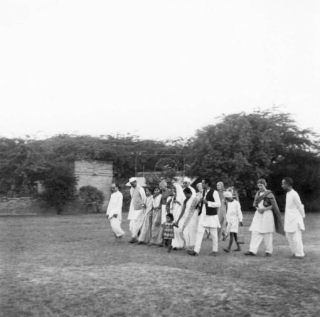 Foto de Mahatma Gandhi y otros caminando en el complejo de la Colonia Bhangi en Delhi, 1946, Pyarelal Nayar, Brijkishan Chandiwalla, Mirabehn, Tara Mahatma Gandhis nieta, Rajkumari Amrit Kaur, Rajendra Prasad, India - Imagen libre de derechos