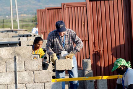 Foto de El ex presidente estadounidense Jimmy Carter junto con voluntarios construyen casas en el 23º Proyecto de Trabajo Jimmy Carter en Patan Village, cerca de Lonavala, Maharashtra, India - Imagen libre de derechos