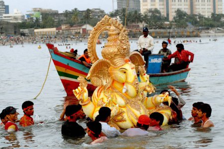 Photo for Devotees immerse a huge Ganesh idol (elephant headed god) in to the sea at Girgaum Chowpatty, ganesh ganpati festival, Bombay now Mumbai, maharashtra, India - Royalty Free Image