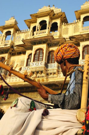 Foto de Músico folclórico frente al edificio del patrimonio, Udaipur, Rajastán, India - Imagen libre de derechos