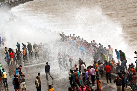 Photo for People enjoying hightide waves at marine drive Bombay ; Mumbai  ;  Maharashtra  ; India NOMR - Royalty Free Image