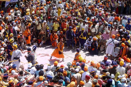 Foto de Guerreros nihang o sij realizando acrobacias con espadas durante las celebraciones de Hola Mohalla en el sahib de Anandpur en el distrito de Rupnagar, Punjab, India - Imagen libre de derechos
