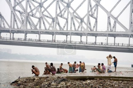 Foto de Actividades en Babu ghat; puente Howrah sobre el río Hooghly en el fondo; Calcuta ahora Kolkata; Bengala Occidental; India - Imagen libre de derechos