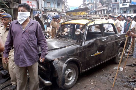 Photo for Policemen inspecting site of bomb blast other taxi damage by explosion at Zaveri Bazaar in busy Kalbadevi area; Bombay Mumbai, Maharashtra, India On August 26th 2003 - Royalty Free Image