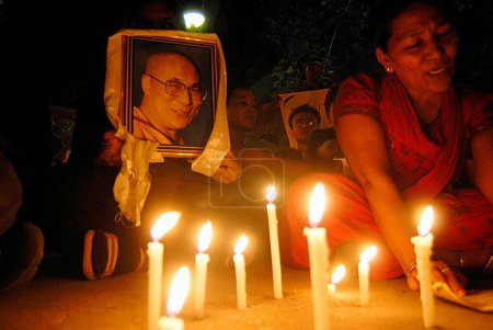 Téléchargez les photos : Tibétains tenant une photographie du dalaï-lama protestant à la lumière de bougies contre la répression chinoise au Tibet, Bombay Mumbai, Maharashtra, Inde - en image libre de droit