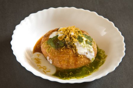 Téléchargez les photos : Collation indienne frite chaat shahi khasta kachori avec coriandre verte au yaourt et chutney tamarin au sev servi dans un bol sur fond noir 23 avril 2010 - en image libre de droit