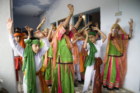 Foto de Niños y niñas de la escuela que usan vestido tradicional de color verde bailando en grupo en la celebración del Día de la Independencia Village Dilwara, Udaipur, Rajastán, India - Imagen libre de derechos