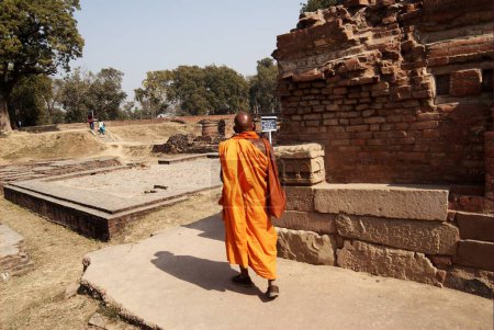 Photo for A Buddhist monk walks in the ruins of Sarnath ; where Lord Gautam Buddha lived near the Dhamekh Stupa Sarnath ; Uttar Pradesh ; India - Royalty Free Image