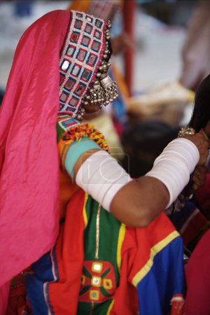 Foto de Mujer nómada vestida con su traje colorido tradicional sentada fuera del Saheb Gurudwara de Sachkhand en Nanded, Maharashtra, India - Imagen libre de derechos