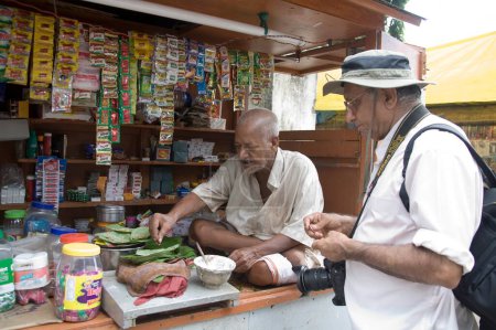 Photo for Old man making pan and customer waiting at Pan Shop Belur Math, Calcutta now Kolkata, West Bengal, India - Royalty Free Image