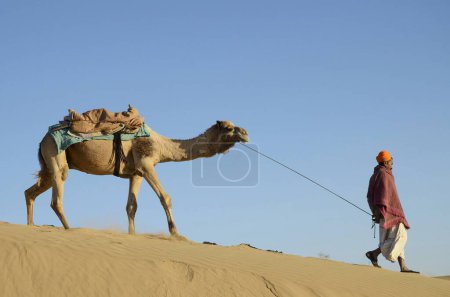 Photo for Man with camel walking on Sand Dunes Khuhri Jaisalmer Rajasthan India - Royalty Free Image