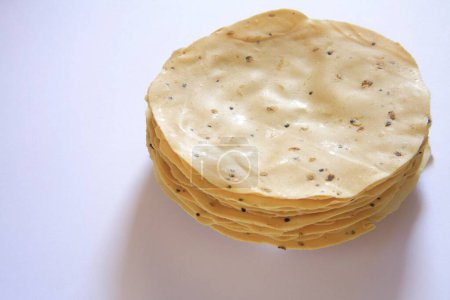 Raw papad poppadoms made of various lentil or cereal flours on white background