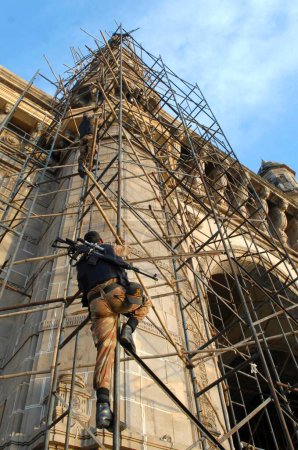 Photo for Commando climbing on scaffold during terrorist attack by deccan mujahideen in Mumbai, Maharashtra, India 26-November-2008 - Royalty Free Image