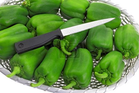 Foto de Green Capsicums Latin Capsicum Annuum en una canasta con dos cuchillos afilados con mango negro, India - Imagen libre de derechos