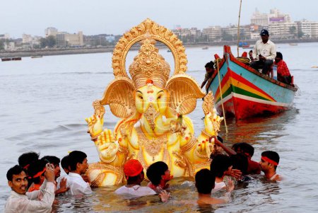 Photo for Devotees immerse a huge Ganesh idol (elephant headed god) in to the sea at Girgaum Chowpatty, ganesh ganpati festival, Bombay now Mumbai, maharashtra, India - Royalty Free Image