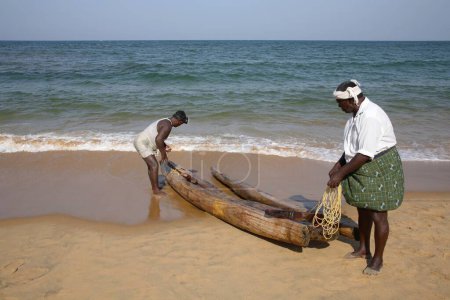 Téléchargez les photos : Bateau radeau composé de quatre rondins attachés ensemble chaque jour que ses pêcheurs d'occasion à la plage de Kovalam, district Thiruvananthapuram, Kerala, Inde - en image libre de droit