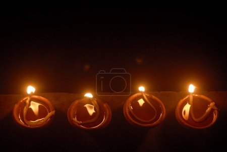 Photo for Aerial view of four small earthen receptacle filled with oil and illuminated for celebrating Gudi Padva Festival ; New year of Hindu religion ; Masunda Tank ; Thane ; Maharashtra ; India - Royalty Free Image
