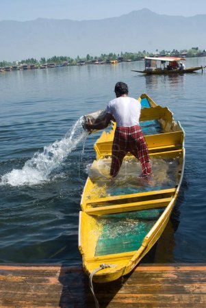 Téléchargez les photos : Un homme jette de l'eau dans le lac dal depuis son bateau Srinagar Jammu-et-Cachemire Inde Asie - en image libre de droit