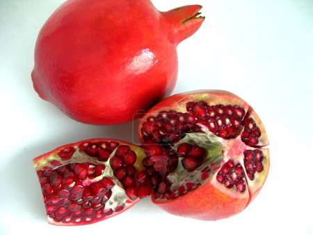 Foto de Frutas, una granada sin cortar completa una fruta de comida medio cortada sobre fondo gris - Imagen libre de derechos