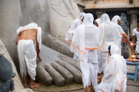 Foto de Devoto tocando pies de estatua de la deidad jaina gomateshvara, Sravanabelagola, Hassan, Karnataka, India - Imagen libre de derechos