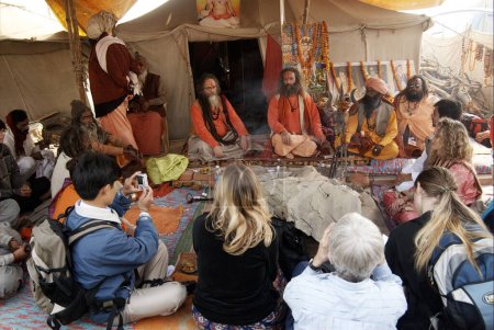 Téléchargez les photos : Sadhus de la Juna Akadha assis avec leurs disciples la plupart d'entre eux étrangers à leur camp pendant l'Ardh Kumbh Mela, Inde - en image libre de droit