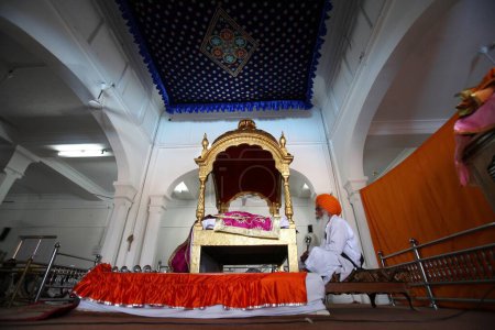 Foto de El clérigo sij agita un batidor sobre el sagrado Guru Granth Sahib en el Anandpur Sahib Gurudwara en el distrito de Rupnagar, Punjab, India - Imagen libre de derechos