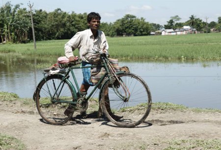 Foto de Hombre caminando por la carretera con su bicicleta, Kishanganj, Bihar, India - Imagen libre de derechos