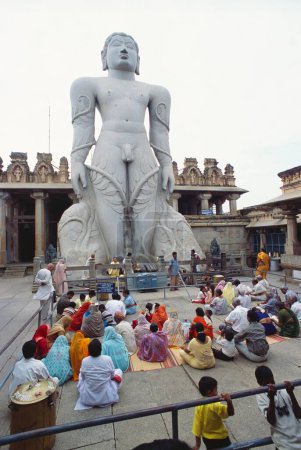 Photo for Jain Devotees praying to 58.8 feet monolithic Statue of jain saint Gomateshwara (Lord Bahubali) in Mahamastakabhisheka (head anointing ceremony) on the Vindhyagiri hill, Shravanabelagola, Karnataka, India - Royalty Free Image
