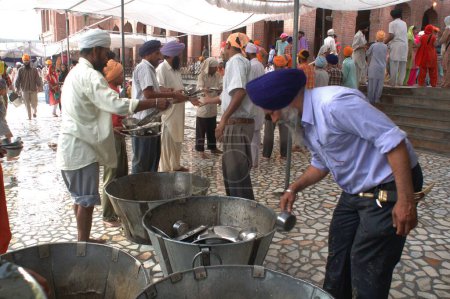 Photo for Langar, community kitchen, free food-guru ka langar, the gurus kitchen introduced by guru Amar Das to melt the caste barriers and to provide free food for thousands of pilgrims through voluntary service, Golden temple, Amritsar, Punjab, India - Royalty Free Image