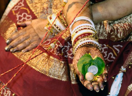 Betel leaf supari and coin in hand palm of bride performing vidhi in marriage ceremony