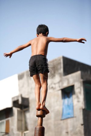 Téléchargez les photos : Jeune garçon effectuant mallakhamb sur poteau en bois - en image libre de droit