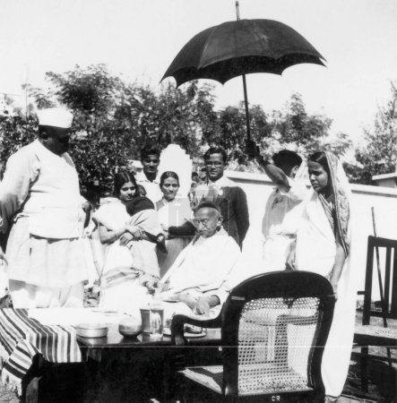 Photo for Mahatma Gandhi, sitting on a table, surrounded by people at Benares Hindu University, Varanasi, 1941, India - Royalty Free Image