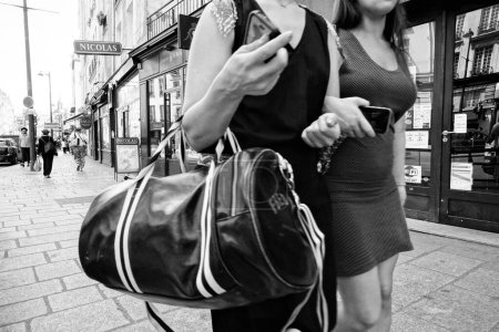 Photo for Two women with bag and mobile phone walking on pavement, Rue Saint Antoine, Paris, France, Europe - Royalty Free Image